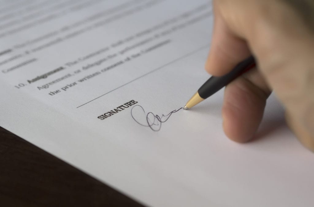 Hand signing a mortgage renewal document; automatically signing without looking at options is a common mortgage mistake