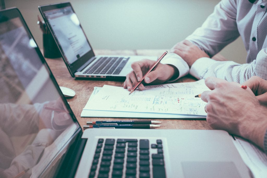 Mortgage broker and client sitting at a desk with laptops and paperwork