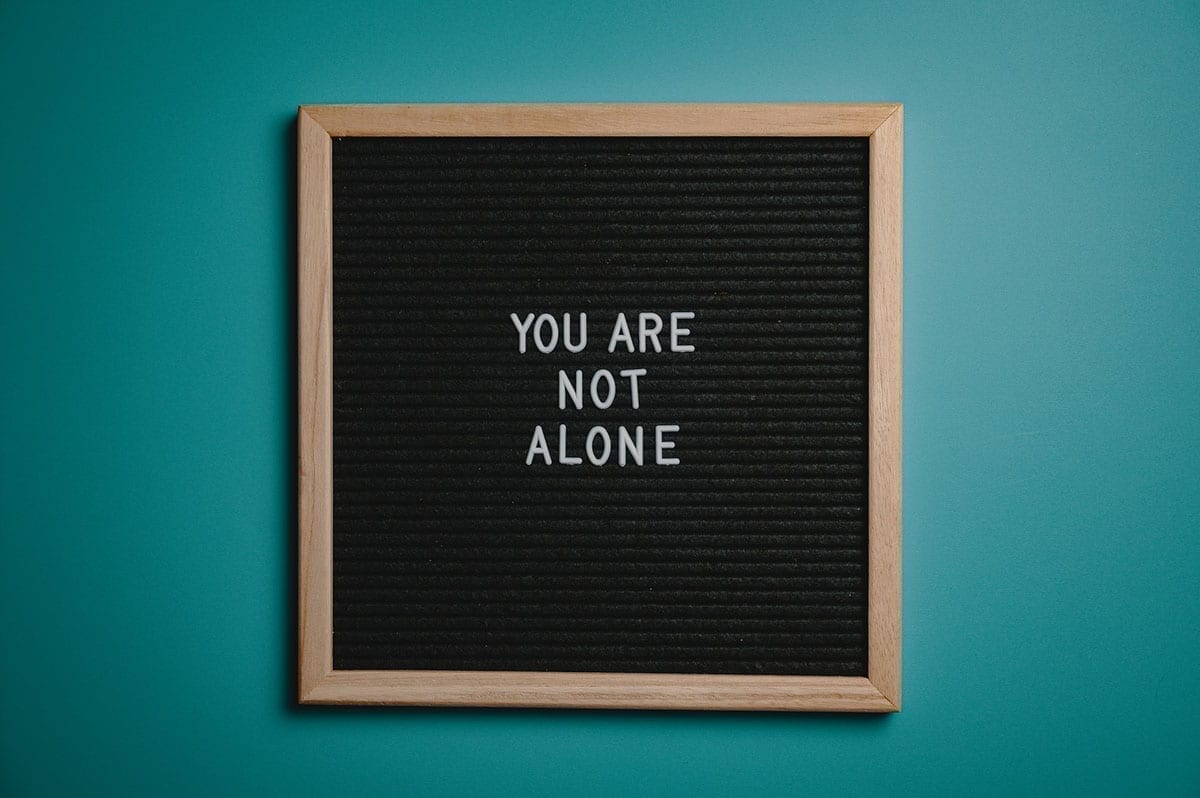 letter board on a turquoise wall that read 'you are not alone', alluding to missing mortgage payments due to the covid-19 pandemic