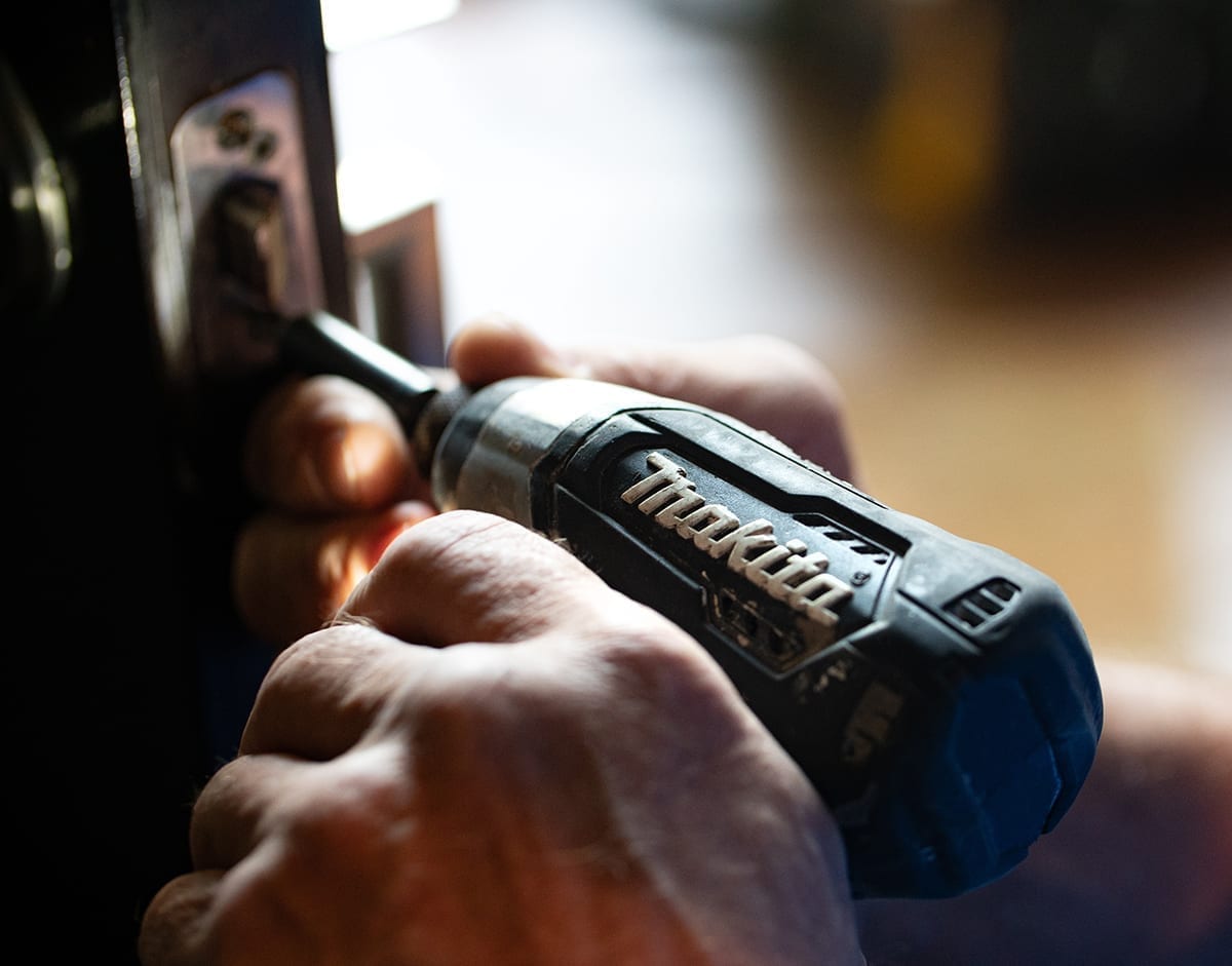 Closeup of hands holding a drill, working on a sliding door, highlighting mortgage refinancing to fund home renovations