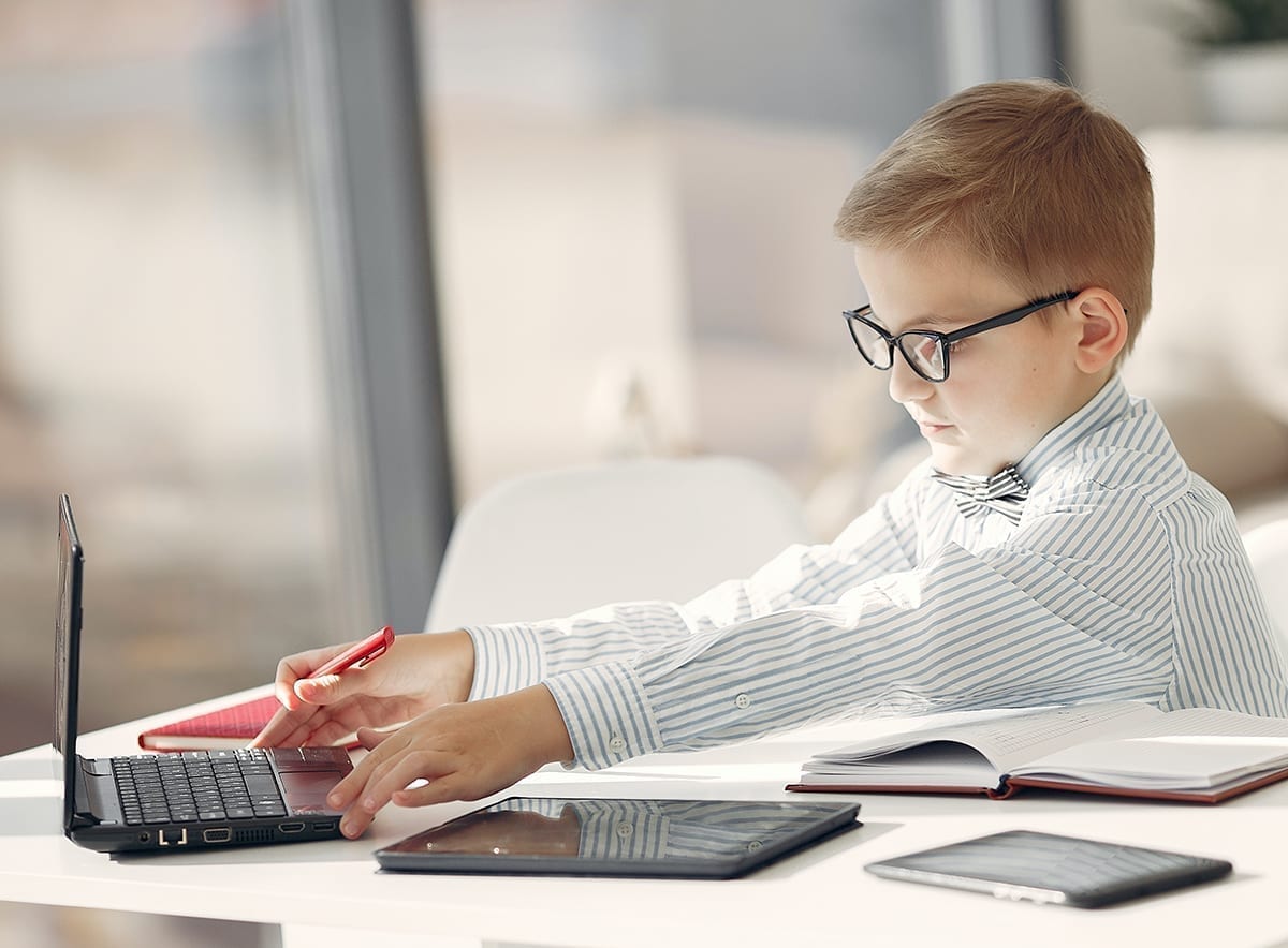 young boy dressed like a business man with bow-tie and glasses on laptop, highlighting that it's never too early to get planning