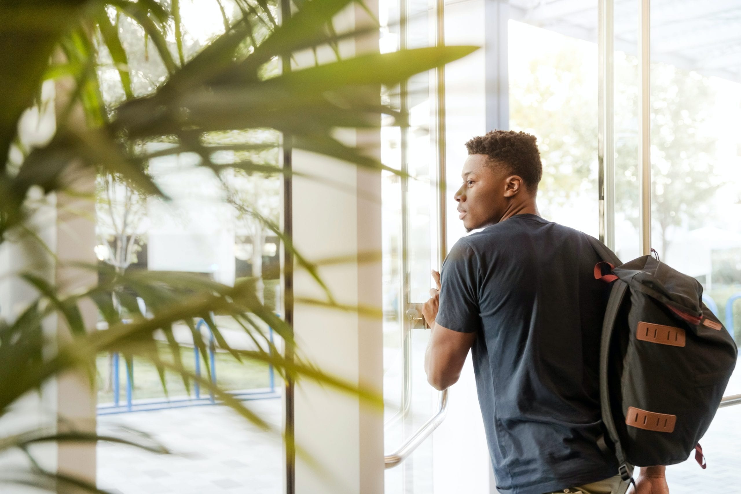 Man exiting a university with a backpack, in reference to qualifying for a mortgage with a student loan