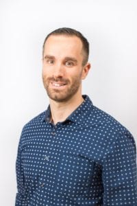 Smiling headshot of Matthew Jackson, Mortgage Broker of Mortgage Okanagan, wearing a dark blue shit with grey dots