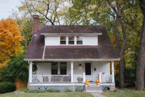 Modest, white Colonial style house with pumpkins lining the front step; relating to private lending mortgages.