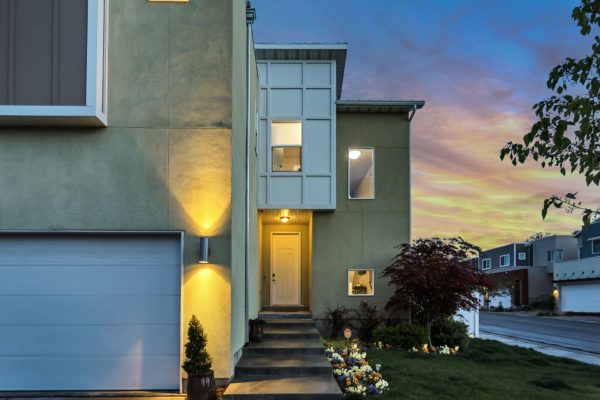 a home at dusk with front lights on and a light over the front door, and a sunset in the background, highlighting property transfer tax in BC