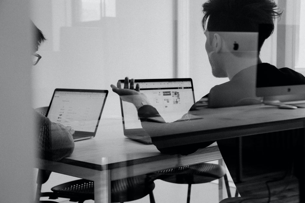 two men at a coffee table with laptops discussing mortgage payments