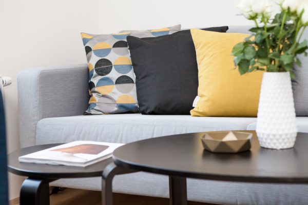 a grey couch in a living room with a brown wood coffee table and white vase with flowers; highlighting mortgages and a conventional mortgage