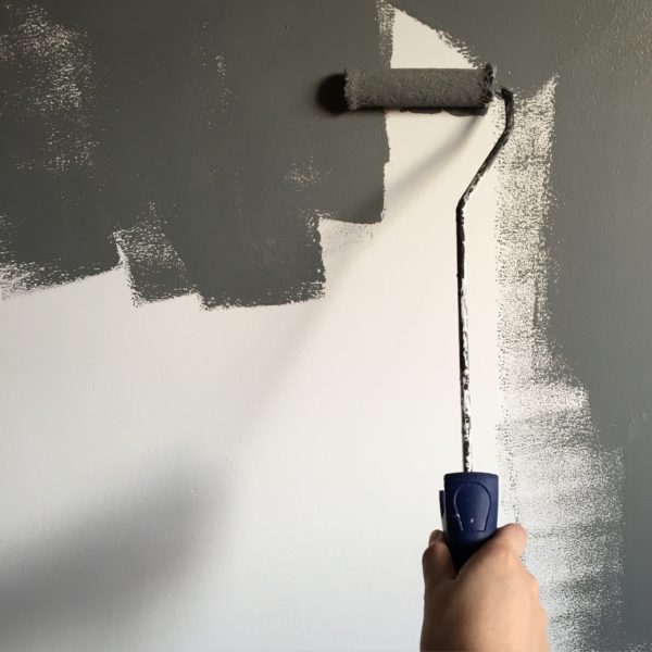 a closeup of a paint roller painting a white wall dark grey, highlighting home renovations and smart financing