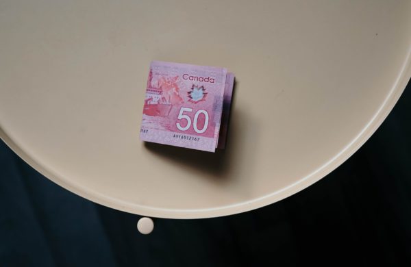 A 50 dollar canadian bill sitting on a beige side table, highlighting the question of whether to lock in your mortgage rate.