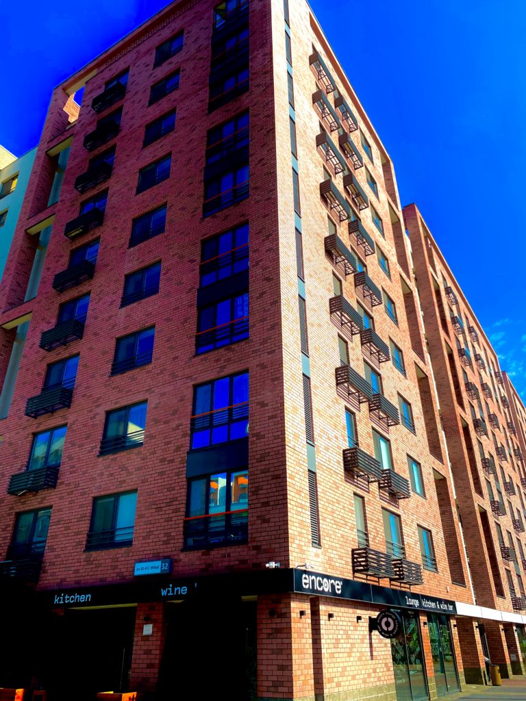 a condo building with a strata, in red brick against a blue sky