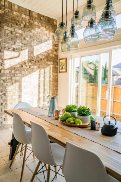 a bright dining room with light through white windows onto a stone wall, with a kitchen table and chairs in the foreground, highlighting mortgage bridge loans