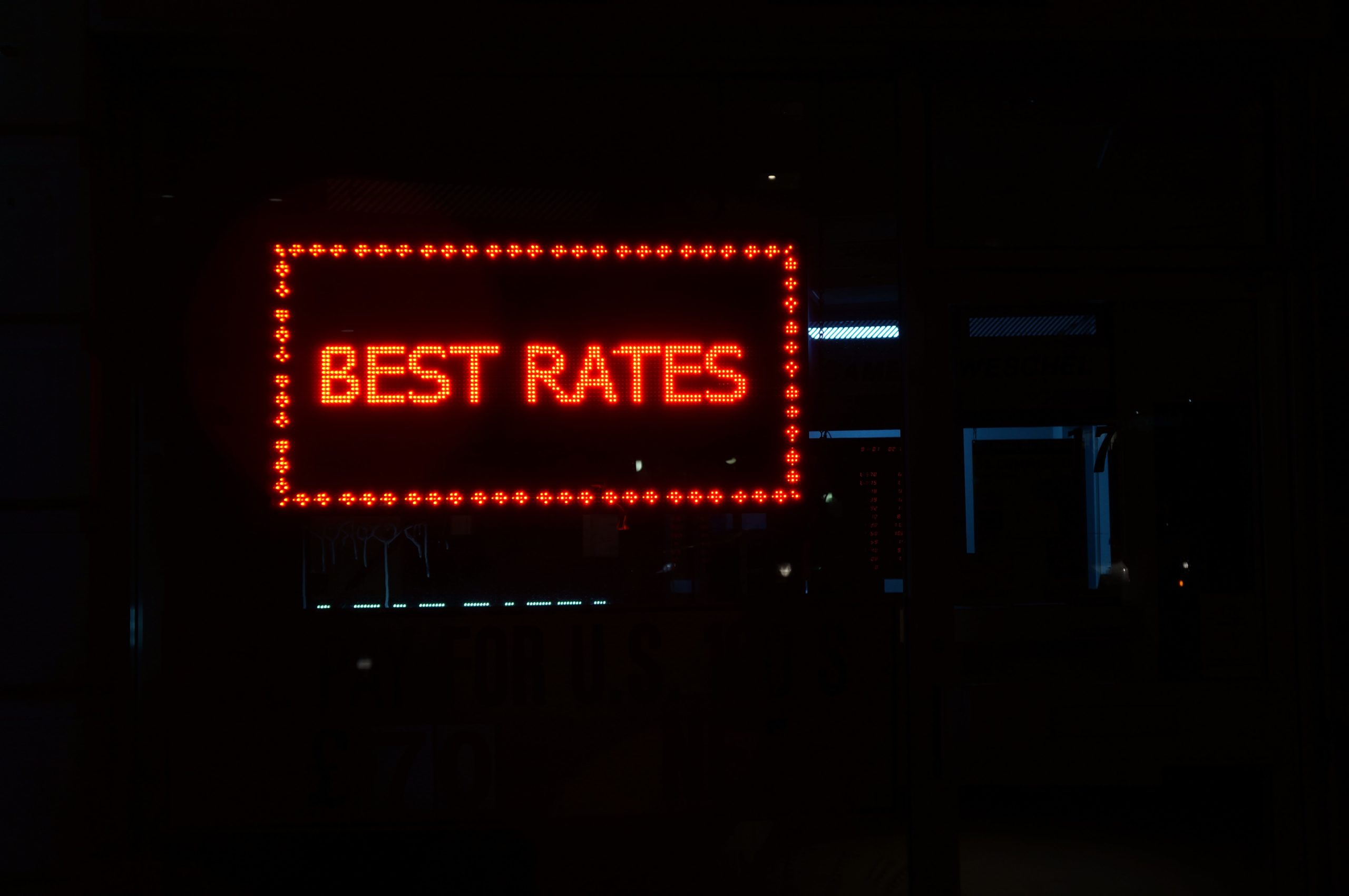a neon red sign against a dark background that reads Best Rates