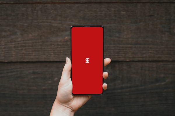 a hand holding a smart phone against a wooden plank background, with the scotia bank logo on the screen, highlighting the penalty for breaking a mortgage