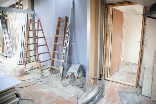 renovation in a home showing a door with no flooring and ladders leaning against a wall, highlighting refinancing for the purpose of home renovations